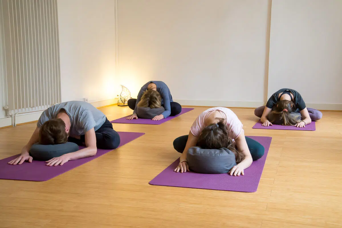 Élèves en posture de l'enfant sur des bolsters, en cours de yin yoga à Lyon Croix-Rousse
