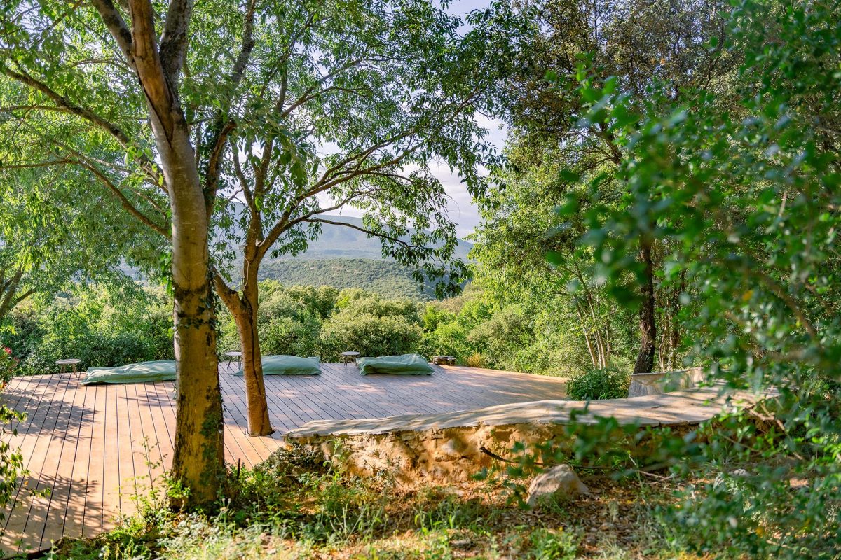 Plateforme en bois pour pratiquer le yoga au milieu des arbres, sur le lieu de la retraite